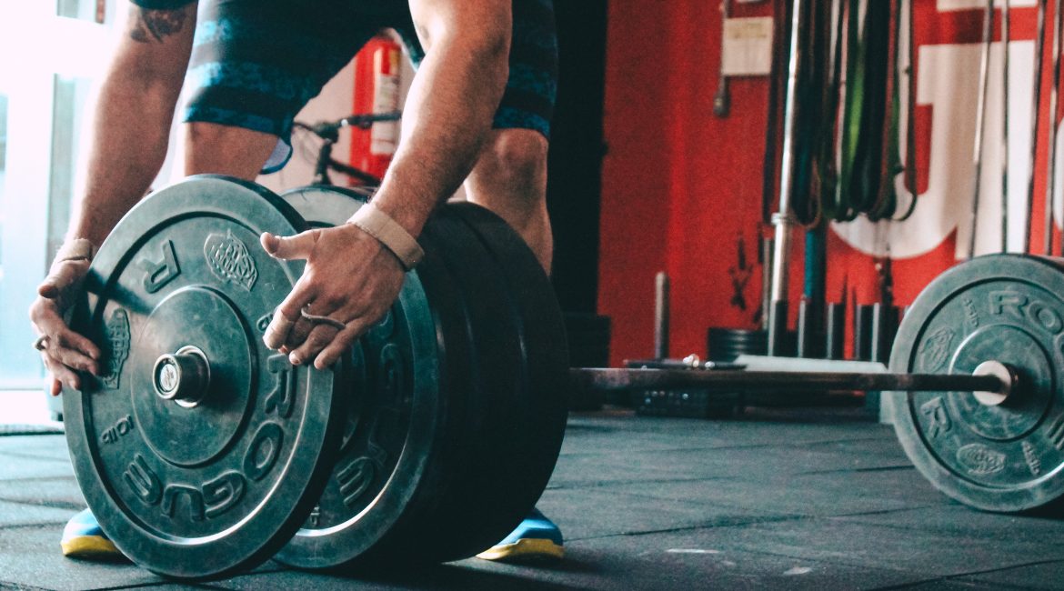 man placing weight plate on barbell